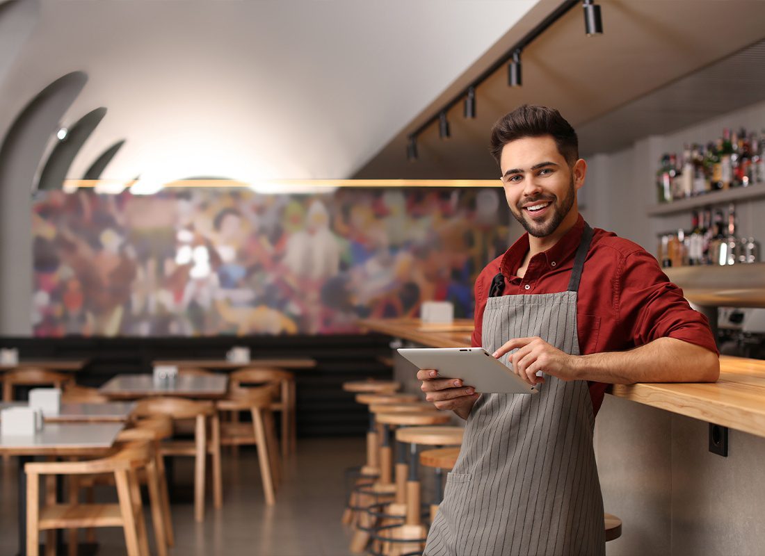 Business Insurance - Young Male Business Owner With Tablet Standing Near Counter in His Cafe