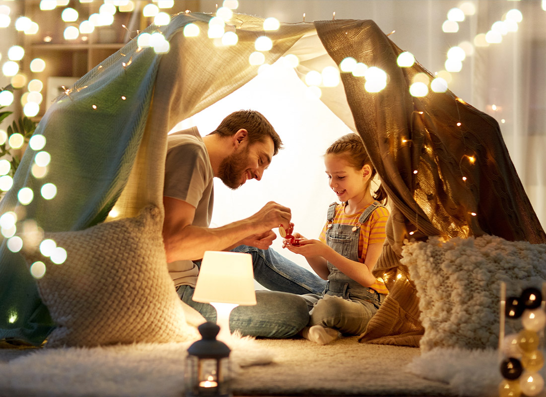 Insurance Solutions - Happy Father and Little Daughter Playing Tea Party in Kids Tent at Night at Home