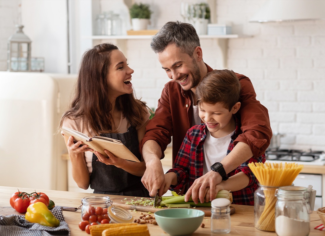 Personal Insurance - Happy Family Laughing Out Loud and Cooking in the Kitchen
